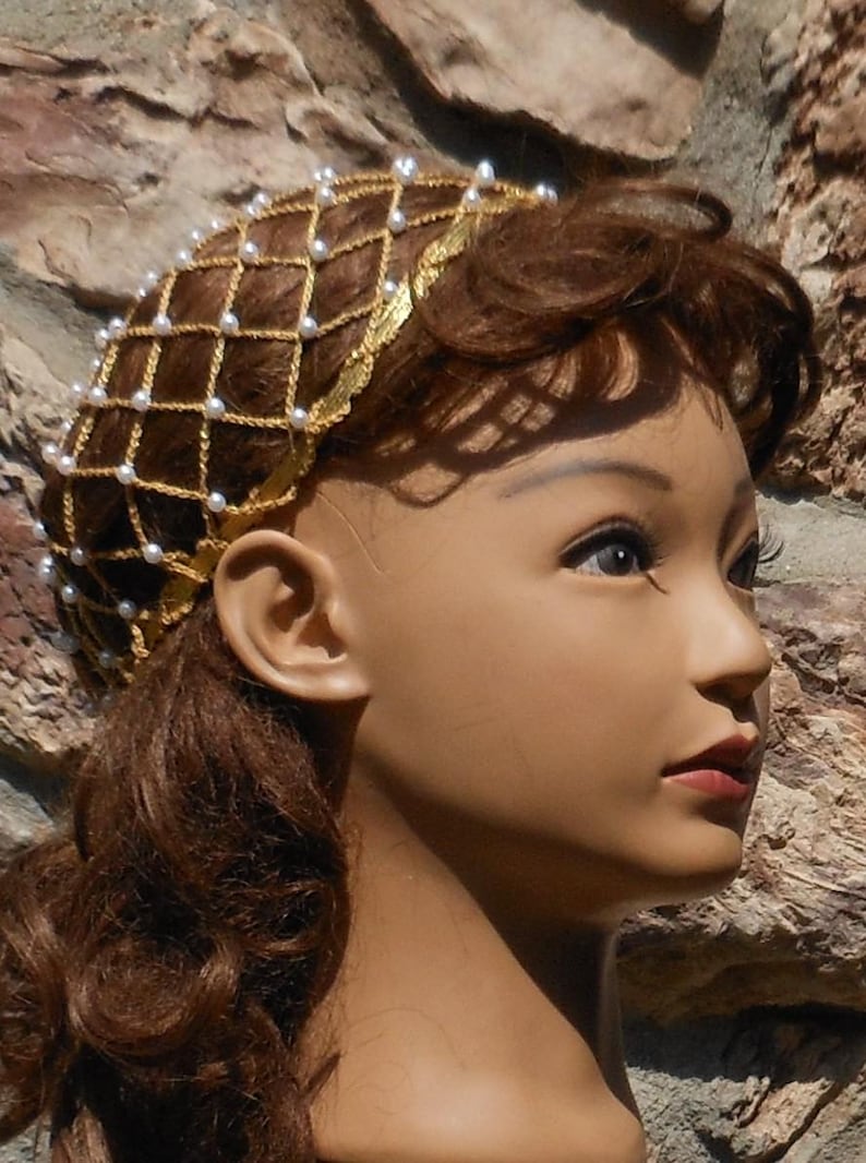 Op de afbeelding: Een gouden draad haarnet met witte parels, gedragen op een mannequinhoofd met bruin haar.