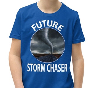 Könnte beinhalten: Ein blaues T-Shirt für Jugendliche mit einem weißen Kreis-Motiv, das einen Tornado und den Text "FUTURE STORM CHASER" zeigt.