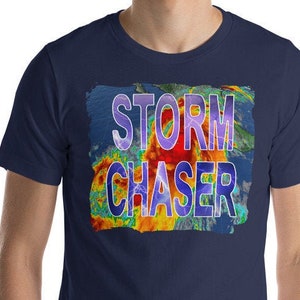 Könnte beinhalten: Ein marineblaues T-Shirt mit einer bunten Grafik eines Wetterradarbildes und dem Text "STORM CHASER" in Lila und Gelb.