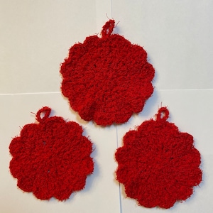 Puede incluir: Tres agarraderas de olla de crochet rojo con un borde festoneado y un lazo para colgar.