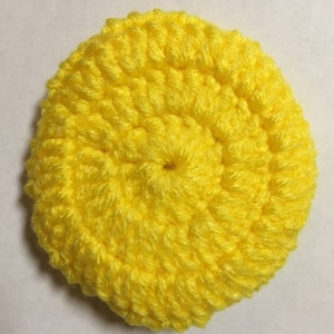 May include: A bright yellow crocheted circle, possibly a coaster or a small decorative piece.