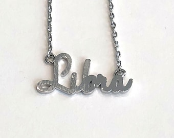 May include: A silver necklace with a cursive 'Libra' pendant.