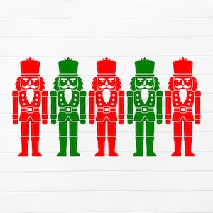 May include: Five festive nutcracker soldier silhouettes in red and green. Each figure has a detailed uniform, hat, and a white beard. The nutcrackers are arranged in a row against a white background with vertical wood grain.