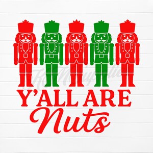 May include: A graphic design featuring five nutcracker figures in red and green. The text "Y'ALL ARE Nuts" is in red script below the figures. The design is on a white background with a wood grain texture.