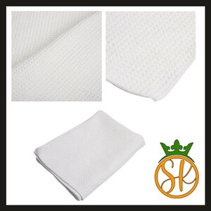 Puede incluir: Pa&ntilde;o de limpieza de microfibra blanco con tejido de gofre. La imagen muestra detalles de primer plano de la textura de la tela, junto con un pa&ntilde;o doblado. El pa&ntilde;o es de color blanco brillante y parece nuevo.