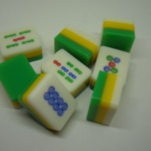 May include: A set of nine green, yellow, and white mahjong tiles with various symbols and numbers. The tiles are made of plastic and have a smooth, glossy finish.