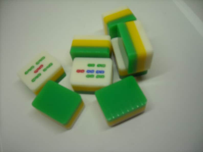 May include: A set of six green, white, and yellow mahjong tiles. The tiles have different symbols and numbers on them.