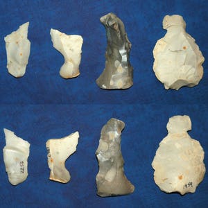 May include: A collection of eight flint tools, some with numbers written on them, on a blue background.