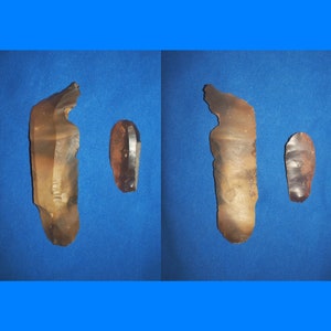 May include: Two brown and tan flint arrowheads, one is long and narrow, the other is short and rounded.