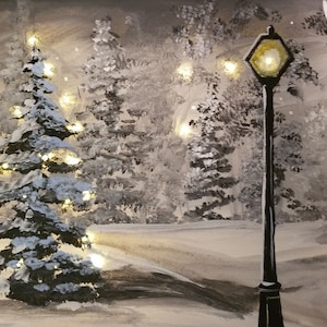 May include: A snowy winter scene with a lit Christmas tree and a street lamp in the foreground. The trees are covered in snow and the ground is white. The street lamp is black with a yellow light.