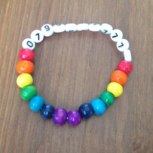 Peut inclure: Un bracelet de perles de couleur arc-en-ciel avec des perles blanches sur lesquelles sont imprim&eacute;s les chiffres 079771.