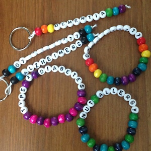 Peut inclure: Quatre bracelets en perles color&eacute;es avec des perles blanches qui &eacute;pellent des conditions m&eacute;dicales : "Type 1 Diabetes", "Nut Allergy", "Alzheimer's" et "Dementia".