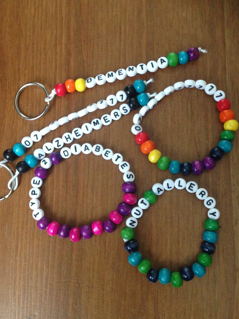 Peut inclure: Quatre bracelets en perles color&eacute;es avec des perles blanches qui &eacute;pellent des conditions m&eacute;dicales : "Type 1 Diabetes", "Nut Allergy", "Alzheimer's" et "Dementia".