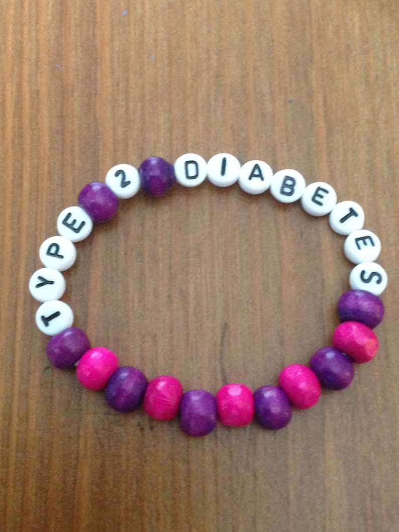 Peut inclure: Un bracelet en perles violettes et roses avec les mots "TYPE 2 DIABETES" &eacute;crits en lettres blanches.