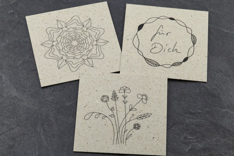 May include: Three blank cards with different black line drawings. The first card has a stylised flower, the second card has a wreath with the text "f&uuml;r Dich" inside, and the third card has a bouquet of flowers.