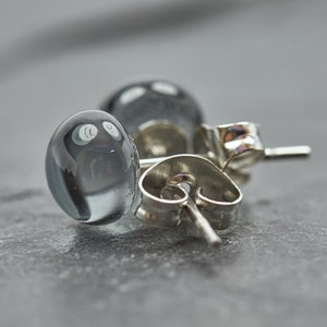 May include: A pair of silver stud earrings with clear glass beads. The beads have a cloudy, opaque appearance.