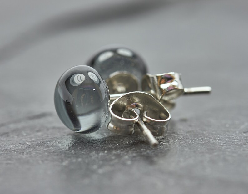May include: A pair of silver stud earrings with clear glass beads. The beads have a cloudy, opaque appearance.