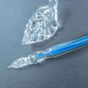 Glazen dippen gevuld met kleurrijke stukjes glas, dippen met sterrenstelsel, penkussen en fles inkt, glaskunstpen, kalligrafiepen