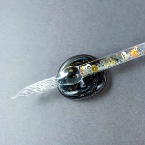 Glazen dippen gevuld met zwevend tandwiel en tandwielen, dippen met sterrenstelsel, penkussen en fles inkt, glaskunstpen, kalligrafiepen