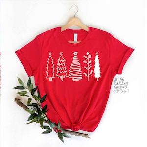 May include: Red t-shirt featuring a white design of five stylised Christmas trees. The trees are all different shapes and sizes, and each has a star on top. The text "tilly & wilbur" is printed in white at the bottom right corner of the shirt.