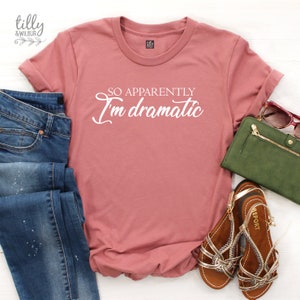 May include: A pink t-shirt with the text "So apparently I'm dramatic" in white lettering.