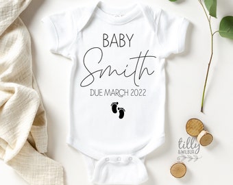 May include: White baby onesie with black text that reads "Baby Smith Due March 2022" and two black footprints.