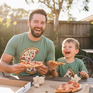 May include: A sage green short-sleeved t-shirt featuring a graphic print of a pizza slice. The shirt is made of a soft cotton fabric and has a crew neckline. The graphic shows a detailed illustration of a pizza slice with pepperoni and basil.