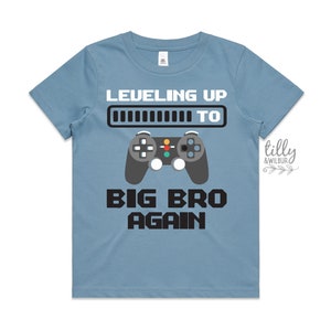 May include: A light blue t-shirt with a black and white graphic of a video game controller and the text "Leveling Up To Big Bro Again".
