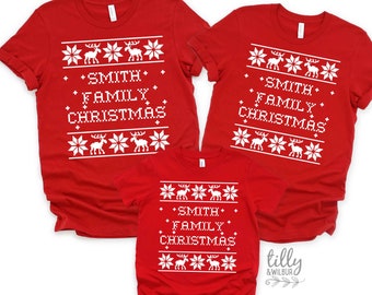 Könnte beinhalten: Drei rote T-Shirts mit kurzen Ärmeln und einem weißen Grafikdruck aus Rentieren und Schneeflocken. Der Text SMITH FAMILY CHRISTMAS ist in einer verpixelten Schriftart in der Mitte gedruckt. Das Logo TILLY & WILBUR ist sichtbar.
