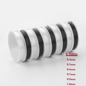 May include: Six spools of black elastic cord in various sizes, ranging from 0.4mm to 1.0mm. The spools are white and arranged in a stack.