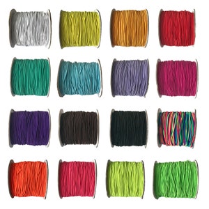 May include: A collection of 15 spools of colourful elastic cord. The cords are wound around cardboard spools and are arranged in three rows of five. The colours include white, yellow, orange, red, green, blue, purple, brown, black, rainbow, orange, pink, lime green, and green.