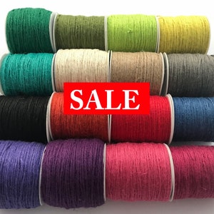 May include: A collection of 12 spools of twine in various colours, including green, beige, yellow, grey, black, orange, red, purple, and pink. The spools are arranged in a pyramid shape and the word "SALE" is printed in red across the middle of the image.