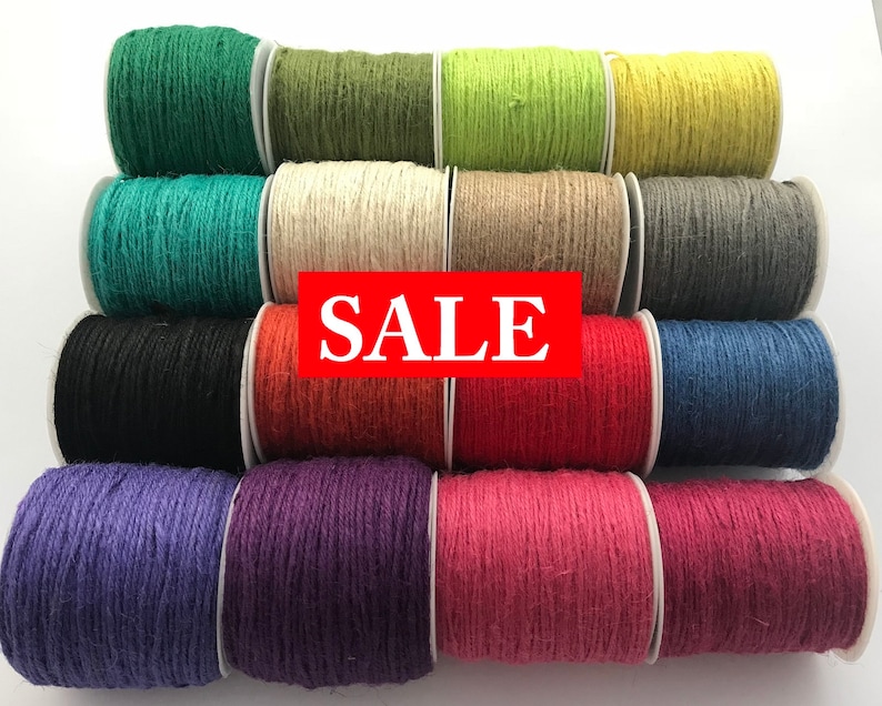 May include: A collection of 12 spools of twine in various colors, including green, beige, yellow, gray, black, orange, red, purple, and pink. The spools are arranged in a pyramid shape and the word "SALE" is printed in red across the middle of the image.