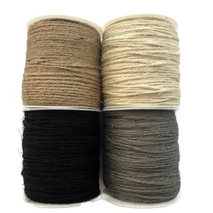 May include: Four spools of twine in different colors: natural, beige, black, and gray. The twine is wound around cardboard spools.
