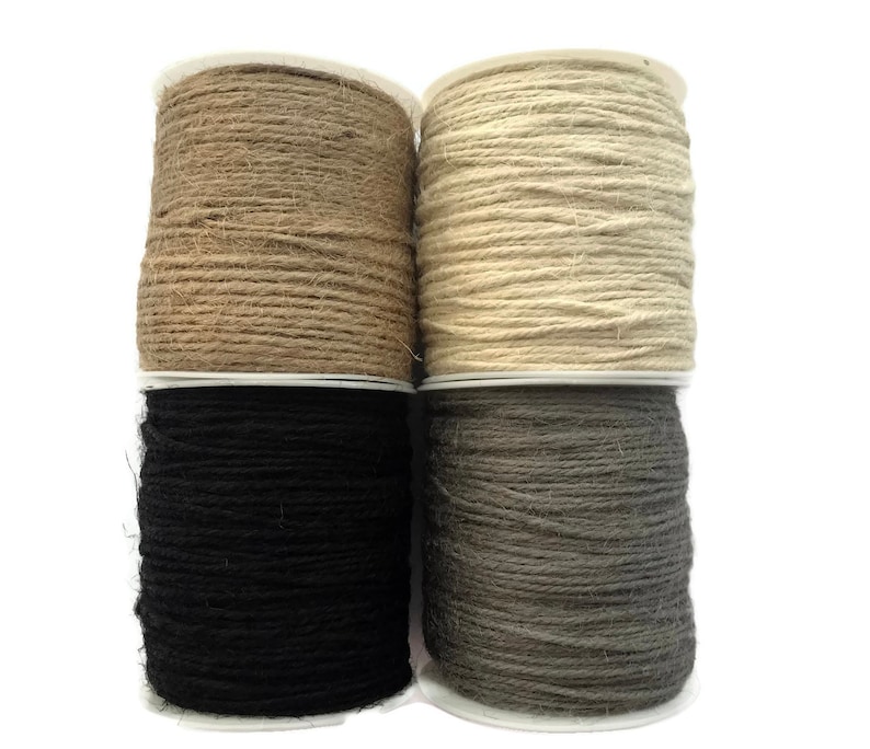 May include: Four spools of twine in different colors: natural, beige, black, and gray. The twine is wound around cardboard spools.