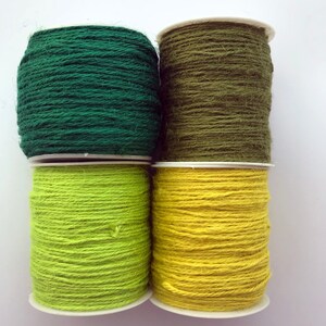 May include: Four spools of twine in green, olive green, lime green, and yellow. The spools are stacked in two rows of two.