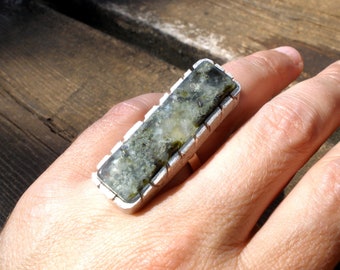 May include: A silver ring with a rectangular green and white stone set in a textured silver band.