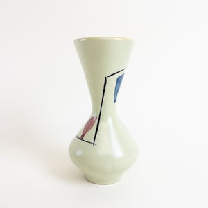 Peut inclure: Un vase en céramique vert clair avec un motif géométrique en noir, bleu et rouge. Le vase a un col étroit et une base large.