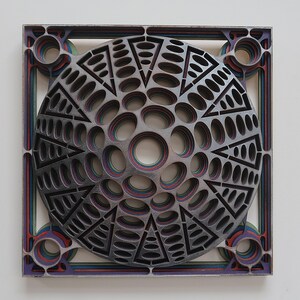 May include: A layered, circular design with concentric circles and triangles, cut from wood and painted in shades of gray, red, blue, and green.