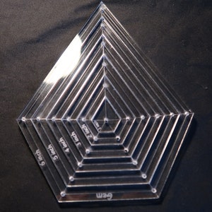 May include: Clear plastic quilting ruler with concentric circles and diamond shapes. The ruler has markings in inches from 1 to 6 inches and 6 cm.