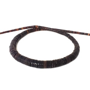 May include: A strand of dark brown and orange round beads made of natural materials. The beads are strung together to form a necklace.