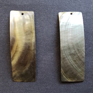 May include: Two rectangular pieces of mother of pearl shell with a hole drilled at the top. The shell has a brown and green iridescent color.