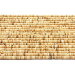 Puede incluir: Una hebra de cuentas de concha beige y marrón. Las cuentas son pequeñas y redondas, y están enhebradas en un hilo transparente.