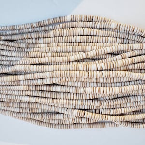 May include: A strand of white and brown shell beads. The beads are small and round, and they are strung together on a thin cord.