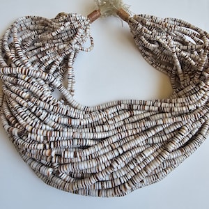 May include: A long strand of white and brown shell beads, strung together to form a necklace. The beads are small and round, and the necklace is tied together with a brown cord.