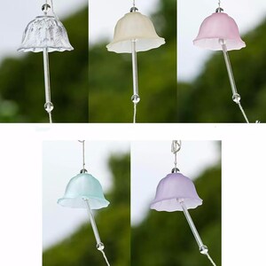 Pode incluir: Uma cole&ccedil;&atilde;o de cinco sinos de vento de vidro em v&aacute;rias cores. Cada sino apresenta um topo em forma de sino com uma borda com babados, uma haste de vidro transparente e uma pequena conta de vidro. As cores incluem transparente, creme, rosa, azul claro e lavanda.