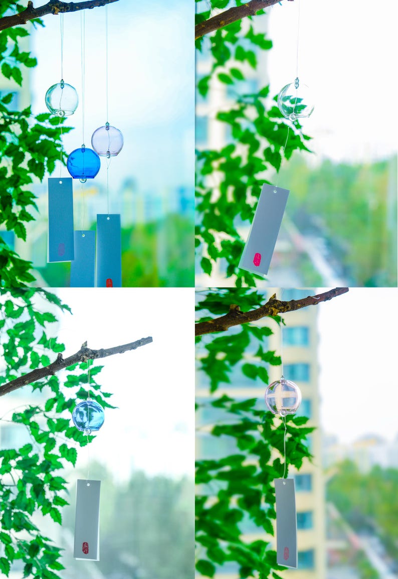 May include: A set of glass wind chimes featuring spherical clear and blue glass bells suspended by thin strings. Each bell is attached to a rectangular light blue paper strip with a small red rectangular accent at the bottom edge.