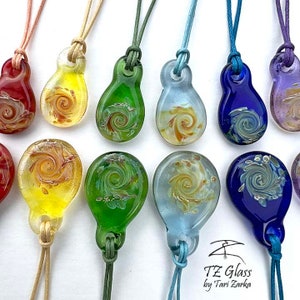 May include: A set of ten glass pendants with a swirling design in various colors, including red, yellow, green, blue, and purple. Each pendant is attached to a cord.