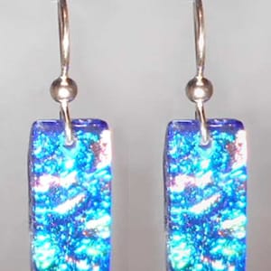May include: A pair of silver dangle earrings with blue iridescent glass rectangular charms. The glass has a textured, bubbly appearance.