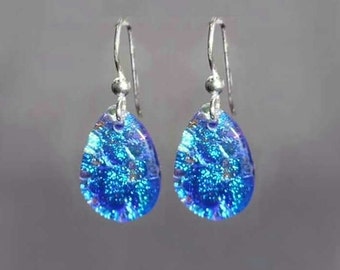 Könnte beinhalten: Ein Paar silberne Ohrhänger mit tropfenförmigen blauen Glasperlen. Die Glasperlen haben eine glitzernde, irisierende Oberfläche.